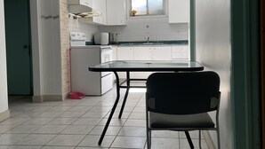 Moderni keittiö, jossa on valkoiset kaapit, ruostumattomasta teräksestä valmistettu pesuallas ja musta tuoli.