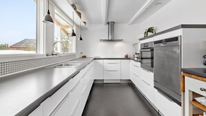A modern kitchen with white cabinetry, a stainless steel oven, and a window providing a view of the outside.