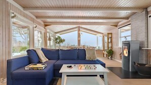 A modern living room with a blue sectional sofa, a white coffee table, and a fireplace.