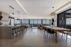 A modern kitchen with a central island, bar stools, and a dining area with a large table and chairs.