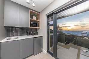 A modern kitchen with grey cabinets, a microwave, and a sink.