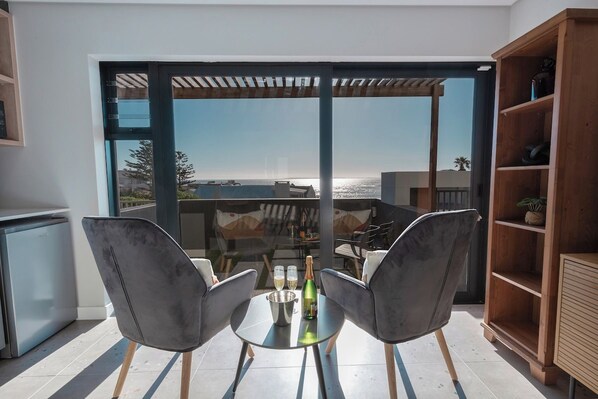 A modern outdoor dining area with two chairs, a table, and a bottle of champagne.