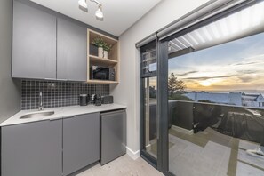 A modern kitchen with grey cabinets, a microwave, and a sink.