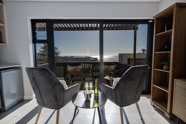 A modern outdoor dining area with two chairs, a table, and a bottle of champagne.