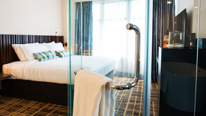 A hotel room with a bed, a glass partition, a shower area, and a desk with a mirror. - Stay Collection Bukit Bintang (Kuala Lumpur)