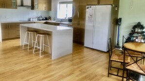Une cuisine moderne dotée d’un îlot central, de planchers en bois et d’un coin repas avec une table et des chaises.