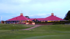 A building with a red roof and a star emblem, surrounded by a well-maintained lawn and a pathway leading to the entrance.