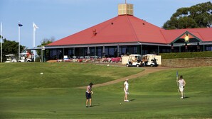 A golf course with a clubhouse featuring a red roof and a star emblem.