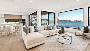 A modern living room with a large sectional sofa, a coffee table, and a view of a body of water. - Luxury Villas Clare De Lune Waterfront (with pool) (Central Coast)