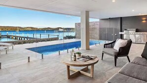 A modern living area with a pool, outdoor furniture, and a view of the water. - Luxury Villas Clare De Lune Waterfront (with pool) (Central Coast)