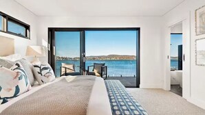 A bedroom with a large bed, a view of the sea, and a balcony with chairs. - Luxury Villas Clare De Lune Waterfront (with pool) (Central Coast)