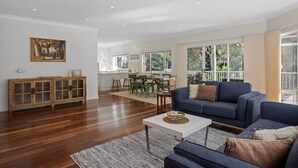 Un espacio habitable amplio con un sofá moderno, una mesa de comedor y una cocina al fondo.