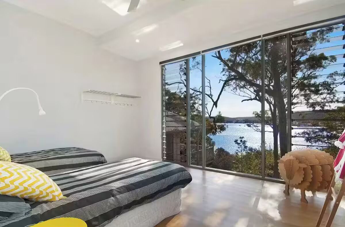 Ein modernes Schlafzimmer mit einem großen Schiebeglastür, die auf einen Balkon mit Seeblick führt.