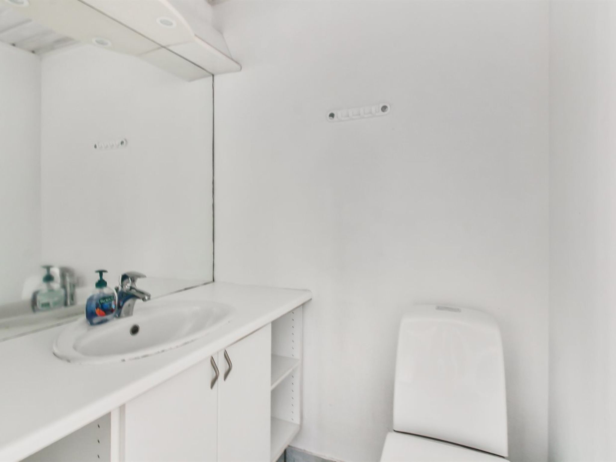 Ein Badezimmer mit einem weißen Waschbecken, einem Spiegel und einer weißen Toilette.