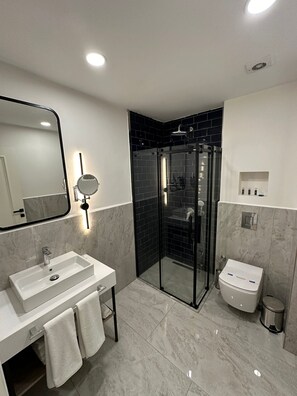 A modern bathroom with a glass-enclosed shower, a white sink, and a toilet. - Prime Bosphorus (Istanbul)
