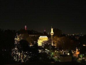 A nighttime view of a cityscape with illuminated buildings, including a prominent tower and a dome structure. - Prime Bosphorus (Istanbul)