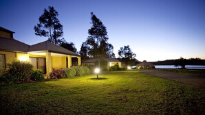 A residential area with houses, a well-maintained lawn, and a body of water in the background. - Club Wyndham Pokolbin Hill (Pokolbin)