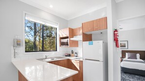 A compact kitchen with a white countertop, wooden cabinets, and a built-in microwave. - Club Wyndham Pokolbin Hill (Pokolbin)