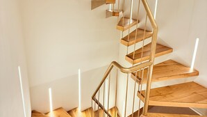 Una escalera espiral moderna con peldaños de madera y barandillas de metal.