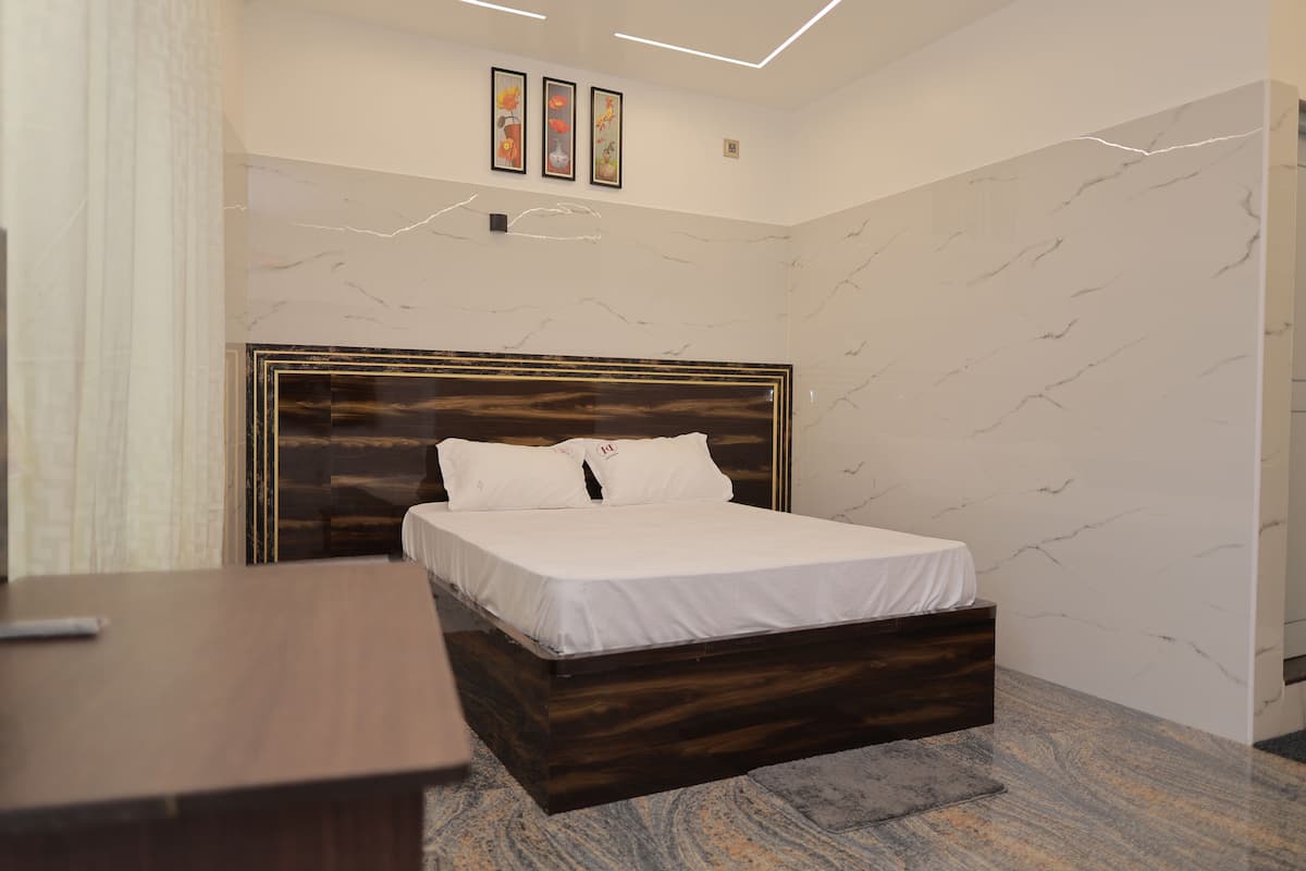 A bedroom with a wooden bed frame, white bedding, and a marble-patterned wall.