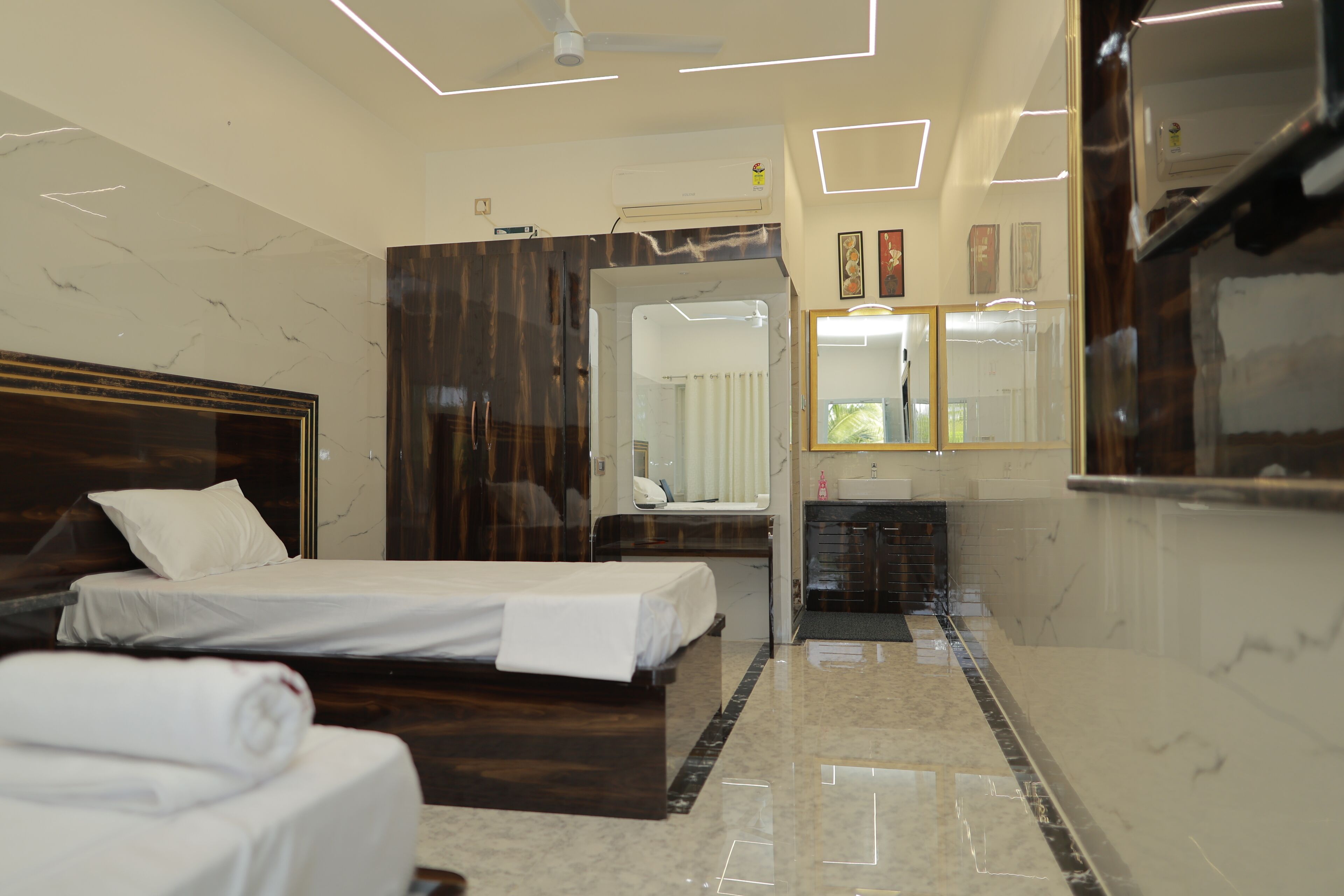 Een moderne hotelkamer met een groot bed, een zithoek, een badkamer met spiegel en een plafondventilator.