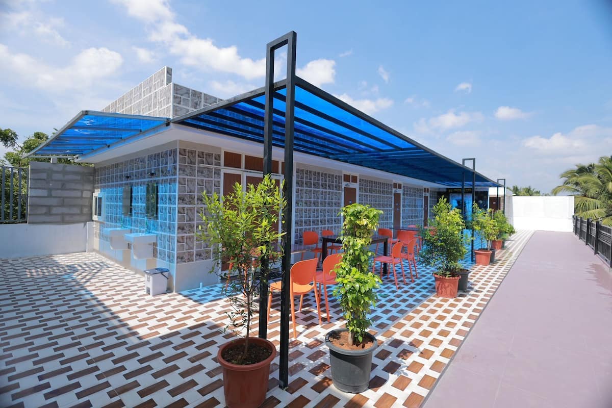 A modern outdoor seating area with a checkered floor, potted plants, and a blue-tinted roof structure.