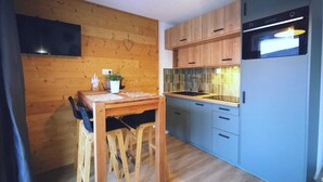 A compact kitchen with wooden cabinets, a built-in oven, and a dining area with a table and chairs.