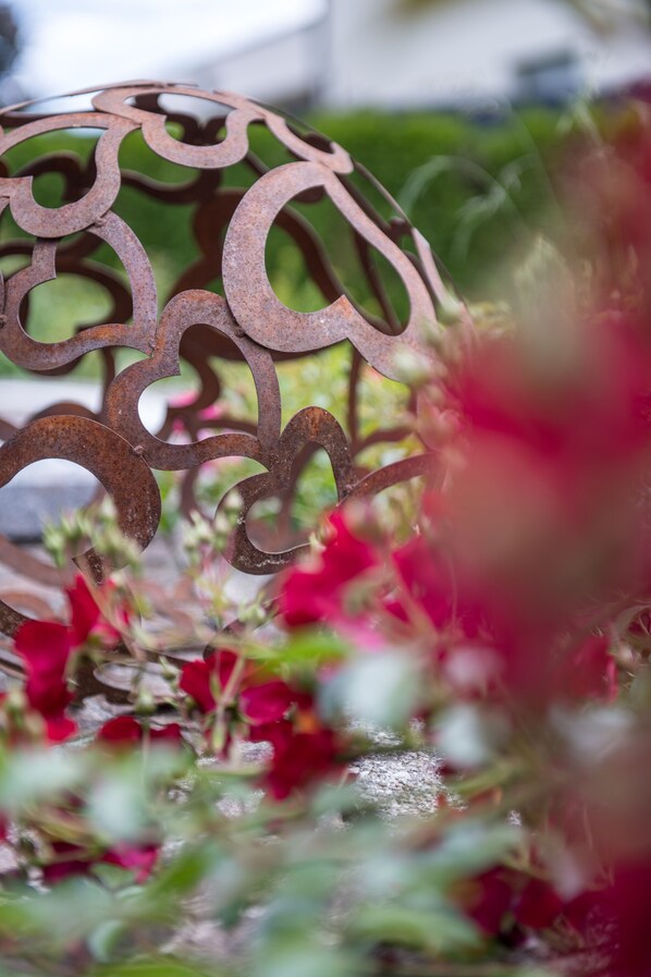 A close-up of a decorative metal piece with a floral arrangement in the background. - WUNDERs Ferienpension  (Poertschach am Woerthersee)