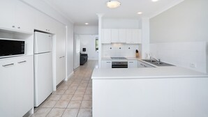 A modern kitchen with white cabinetry, a built-in oven, and a stainless steel sink.