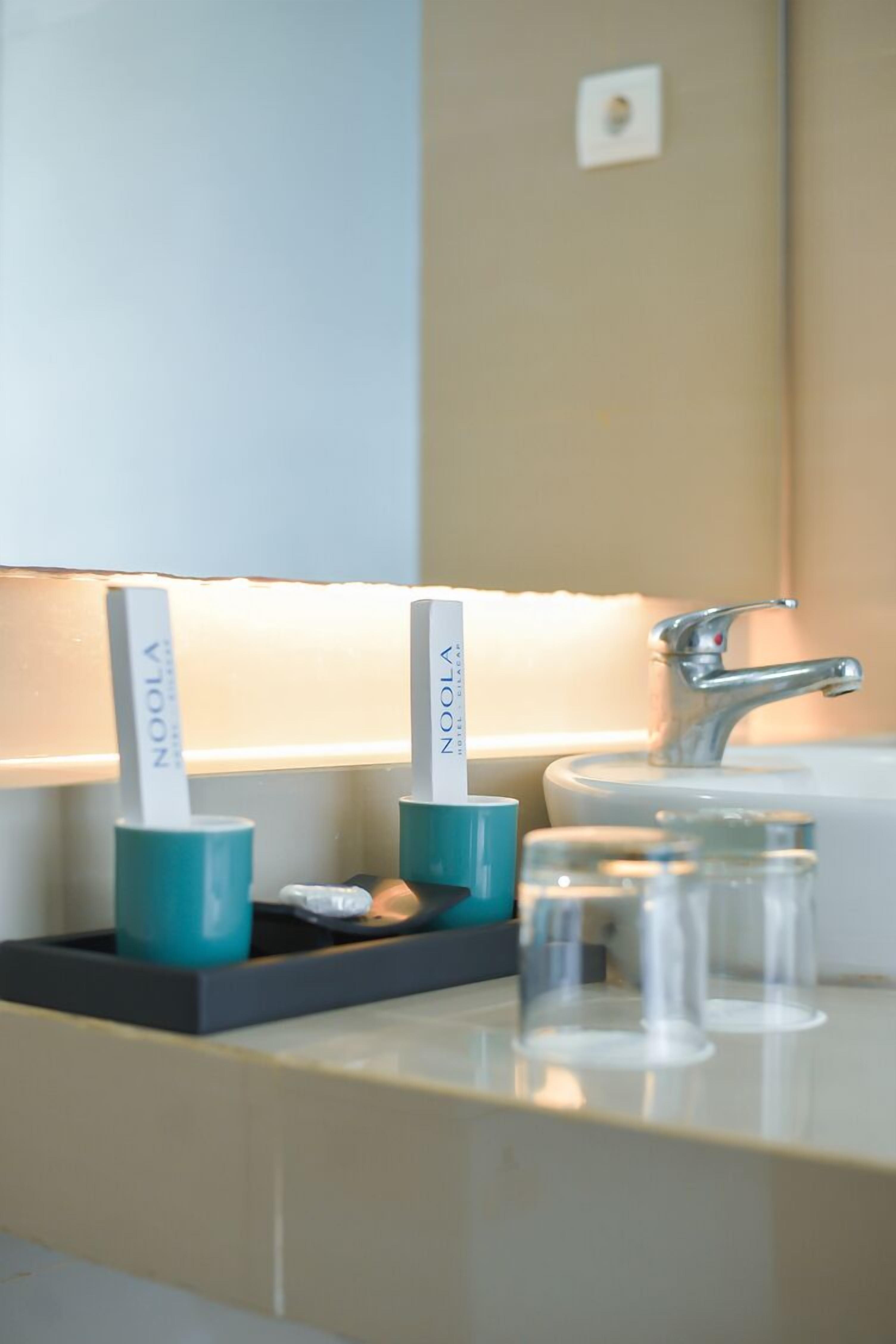 A bathroom with a sink, two toothbrush holders, and three glasses on the counter.