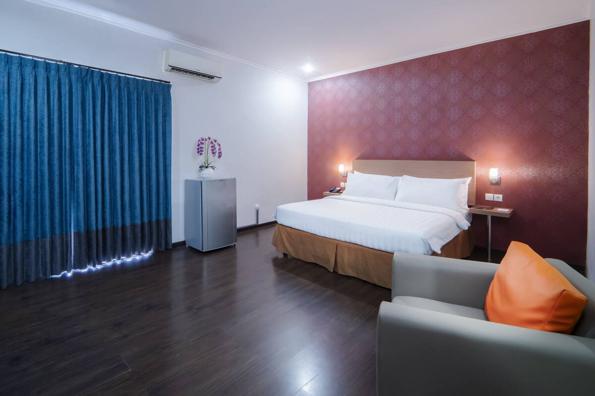 A hotel room with a bed, a desk, a chair, and a curtain.