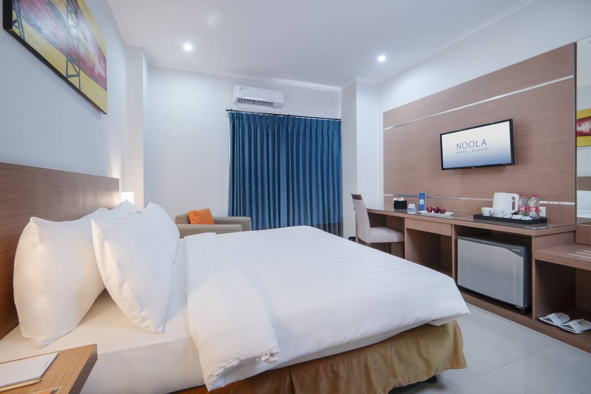 A hotel room with a bed, desk, chair, and TV.