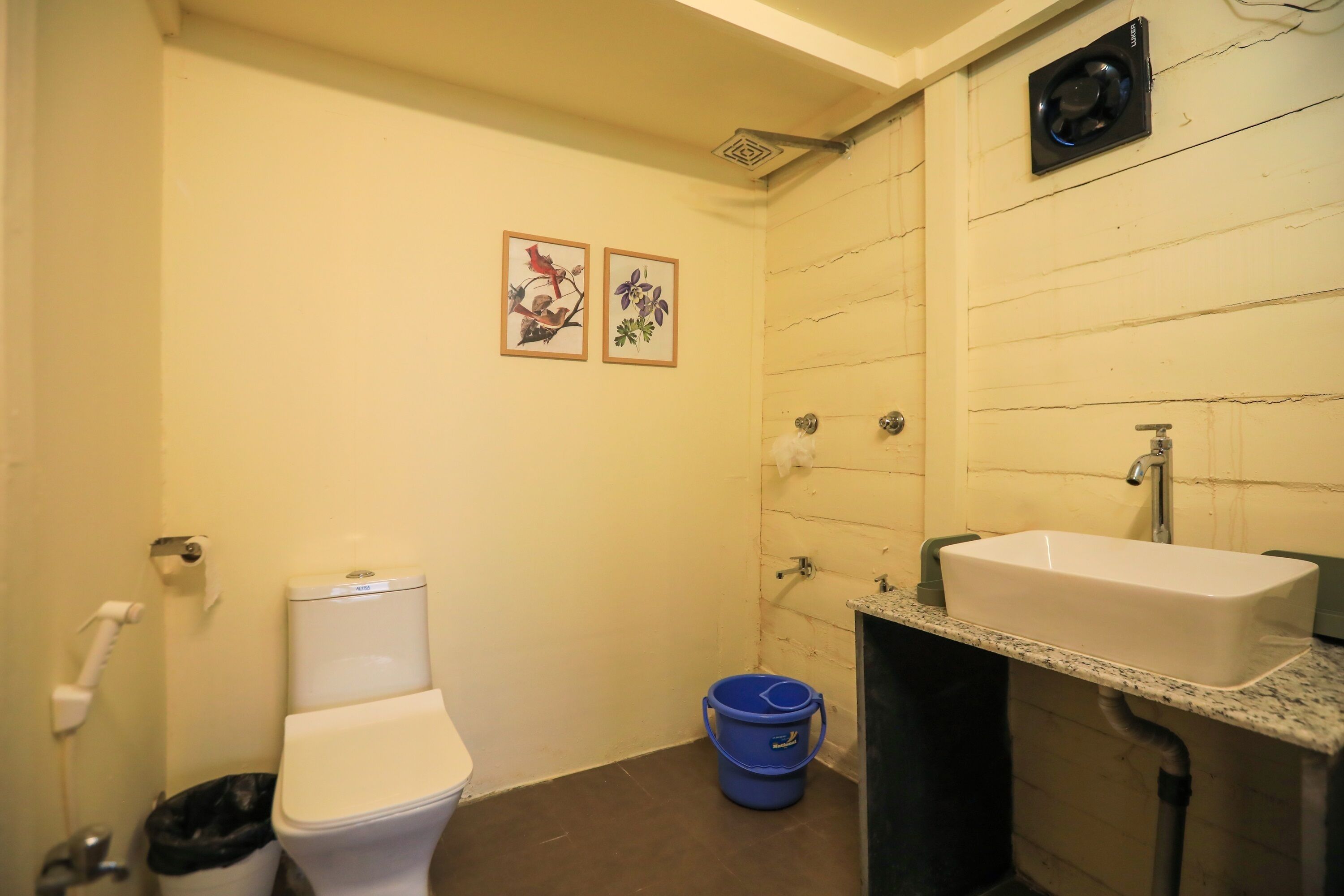 Baño pequeño con inodoro, lavamanos y un cubo azul.