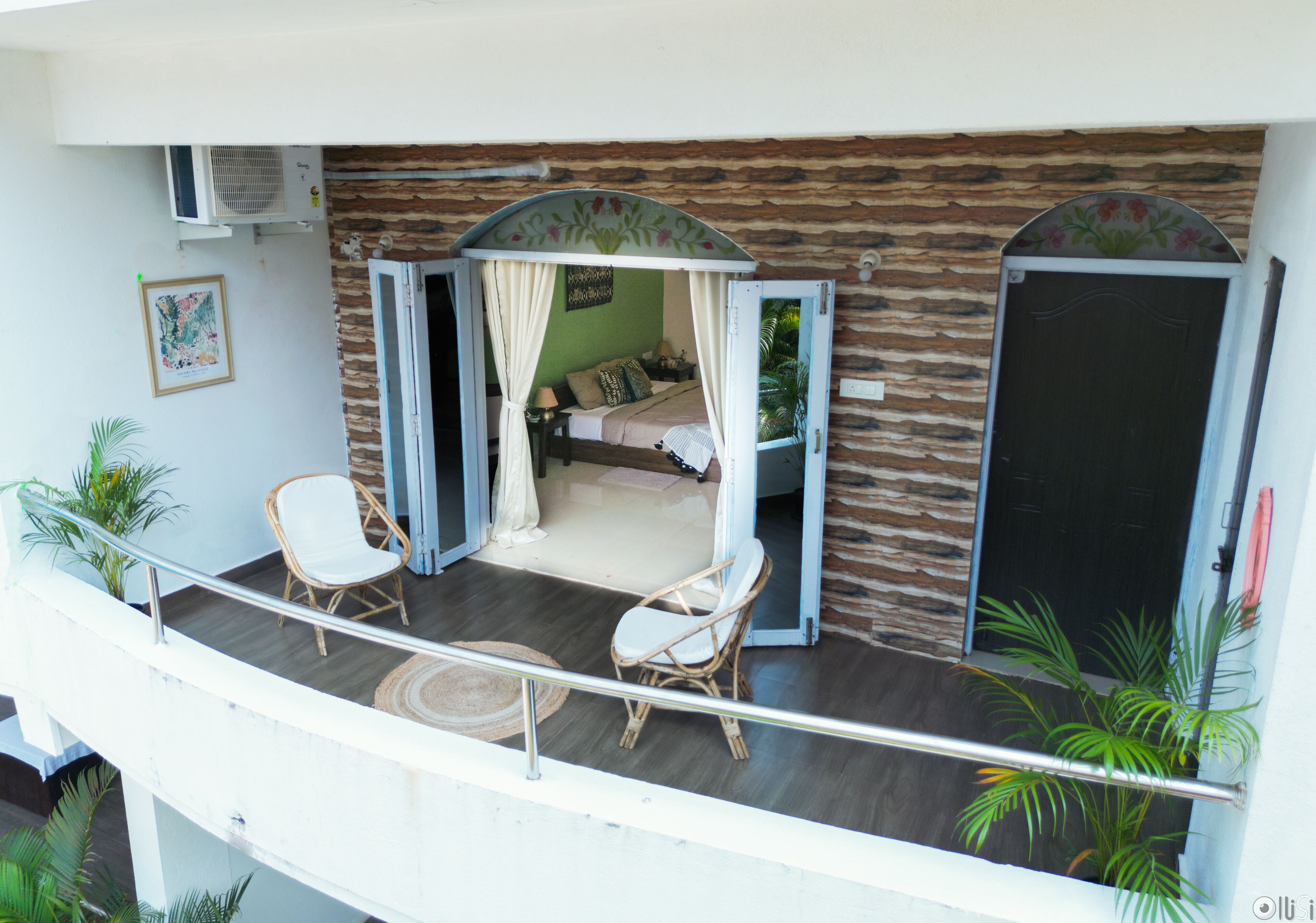 A balcony with a bed, two chairs, and a small table.