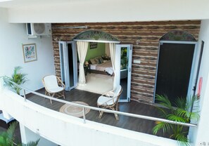 A balcony with a bed, two chairs, and a small table. - Woodpegger By The Beach (Mandrem)