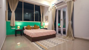A bedroom with a bed, nightstands, a lamp, a window with curtains, an air conditioning unit, and a sliding glass door. - Woodpegger By The Beach (Mandrem)