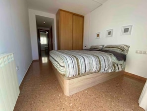 A bedroom with a bed, a wooden wardrobe, and a radiator. - Con Pk y Wifi. Oasis Familiar a 30 Coche de Bcn (Terrassa)
