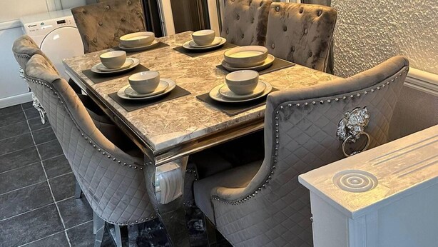 Un coin repas avec une table en marbre, six chaises et un lave-vaisselle à l’arrière-plan.