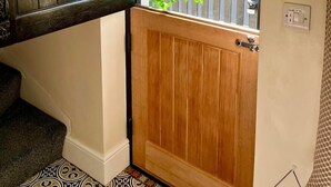 Een houten deur met een klein raam, een spiegel erboven en een potplant ervoor.