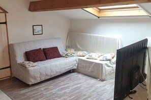 Cozy retreat with a loft-style ceiling, tufted sofa, and a comfortable bed with striped bedspread.