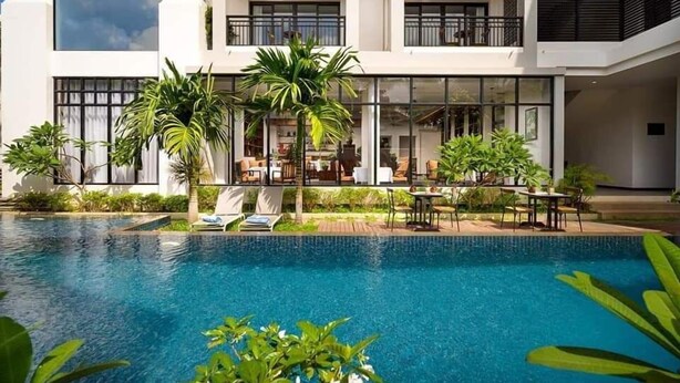 A modern hotel with a pool, outdoor seating, and lush greenery. - Angkor Style Resort (Siem Reap)