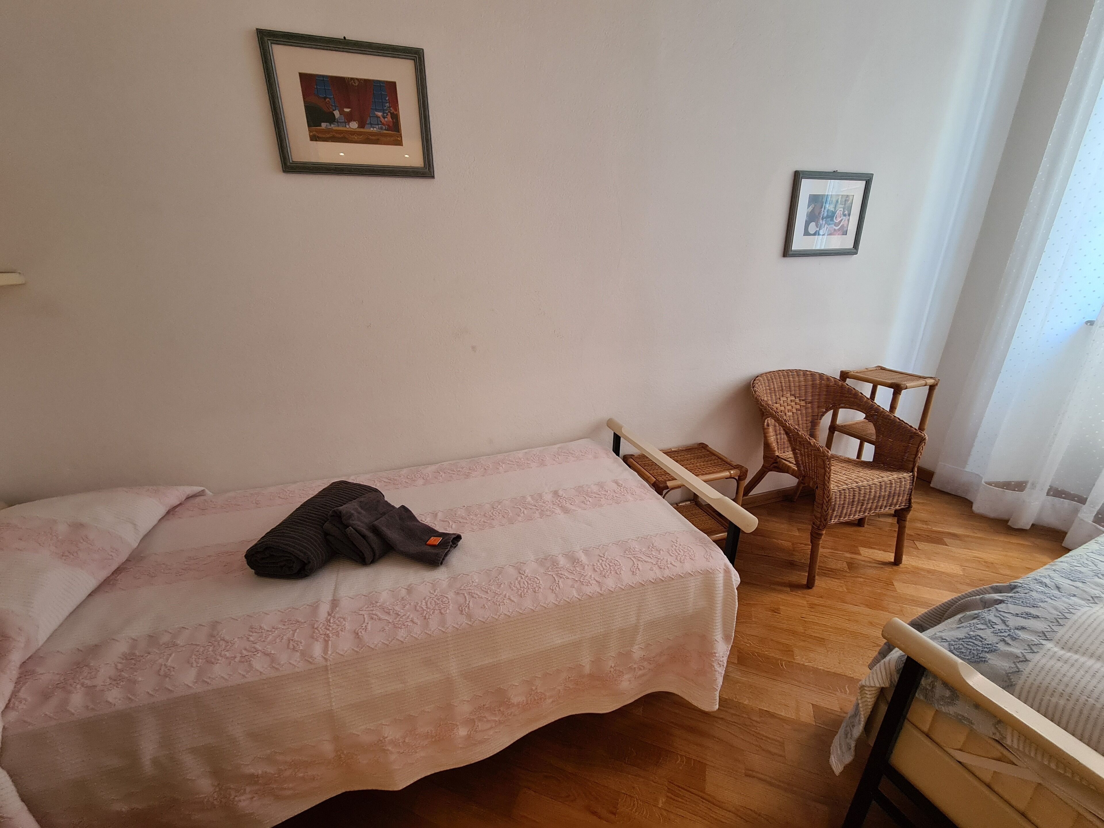 A bedroom with a single bed, a chair, and two framed pictures on the wall.