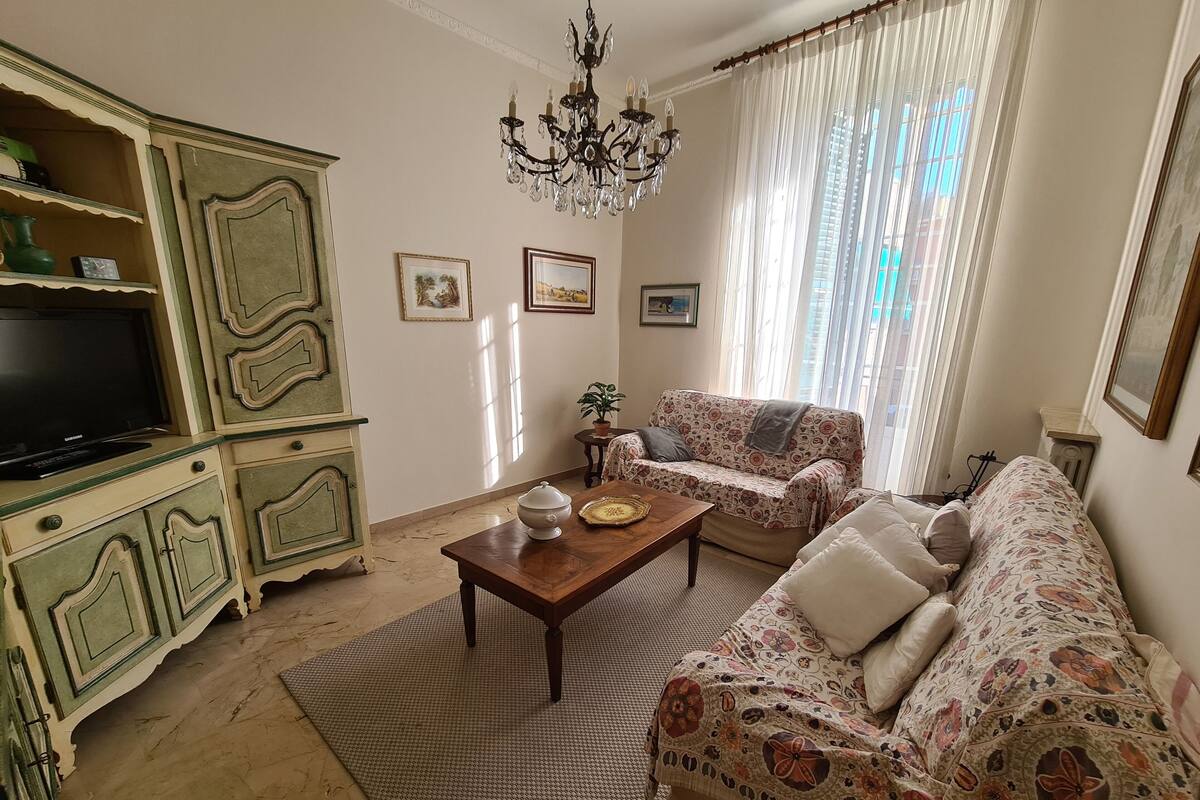 Una sala de estar con un sofá, una televisión, una araña y una alfombra estampada.