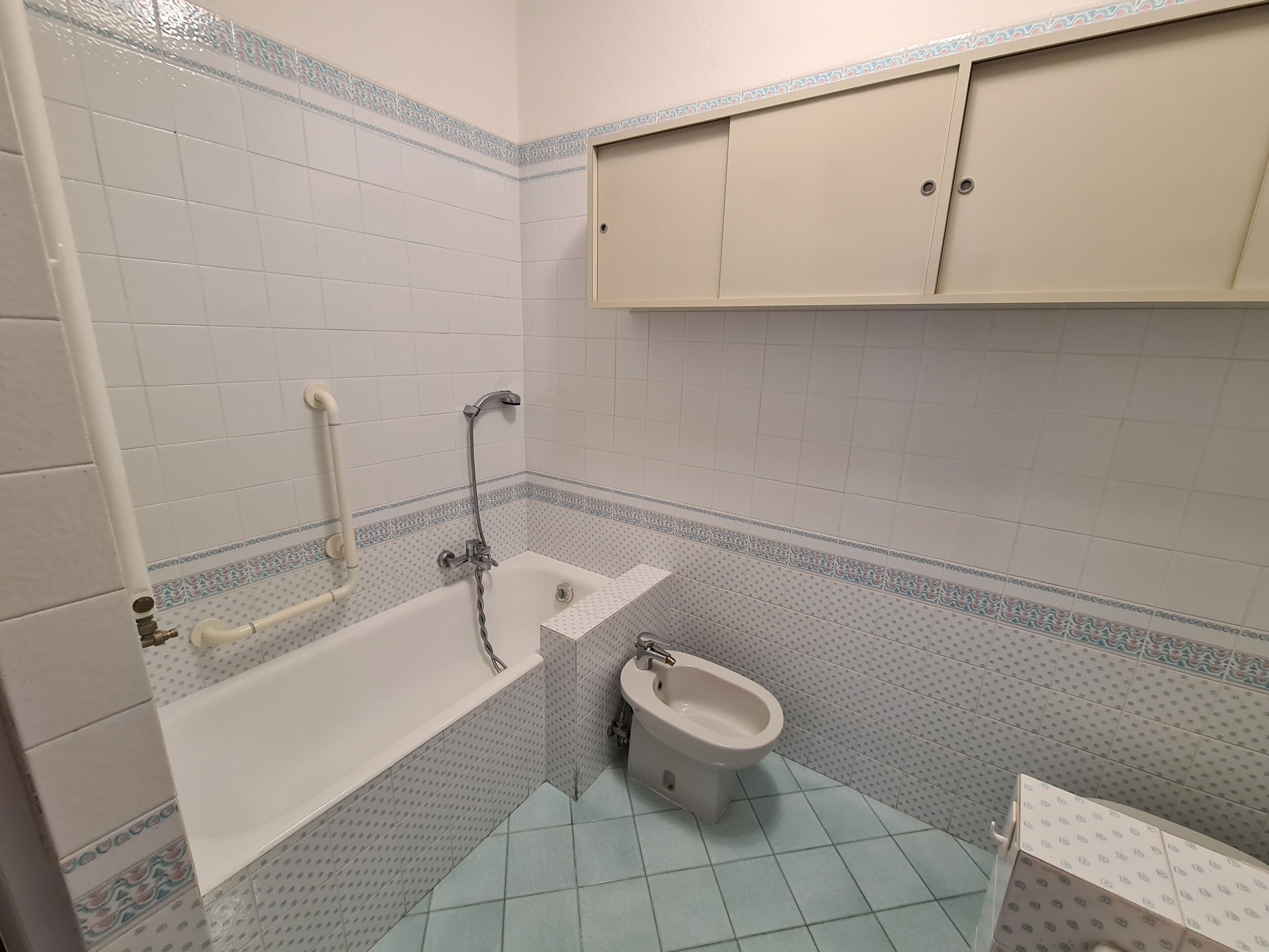 A bathroom with a bathtub, a bidet, and a cabinet.
