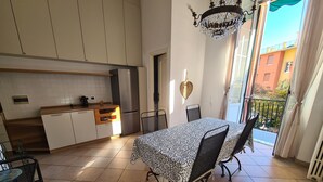 A kitchen with white cabinets, a stainless steel refrigerator, and a dining area with a patterned tablecloth and metal chairs. - Santa in Caruggio- PortofinoVacanze (Santa Margherita Ligure)