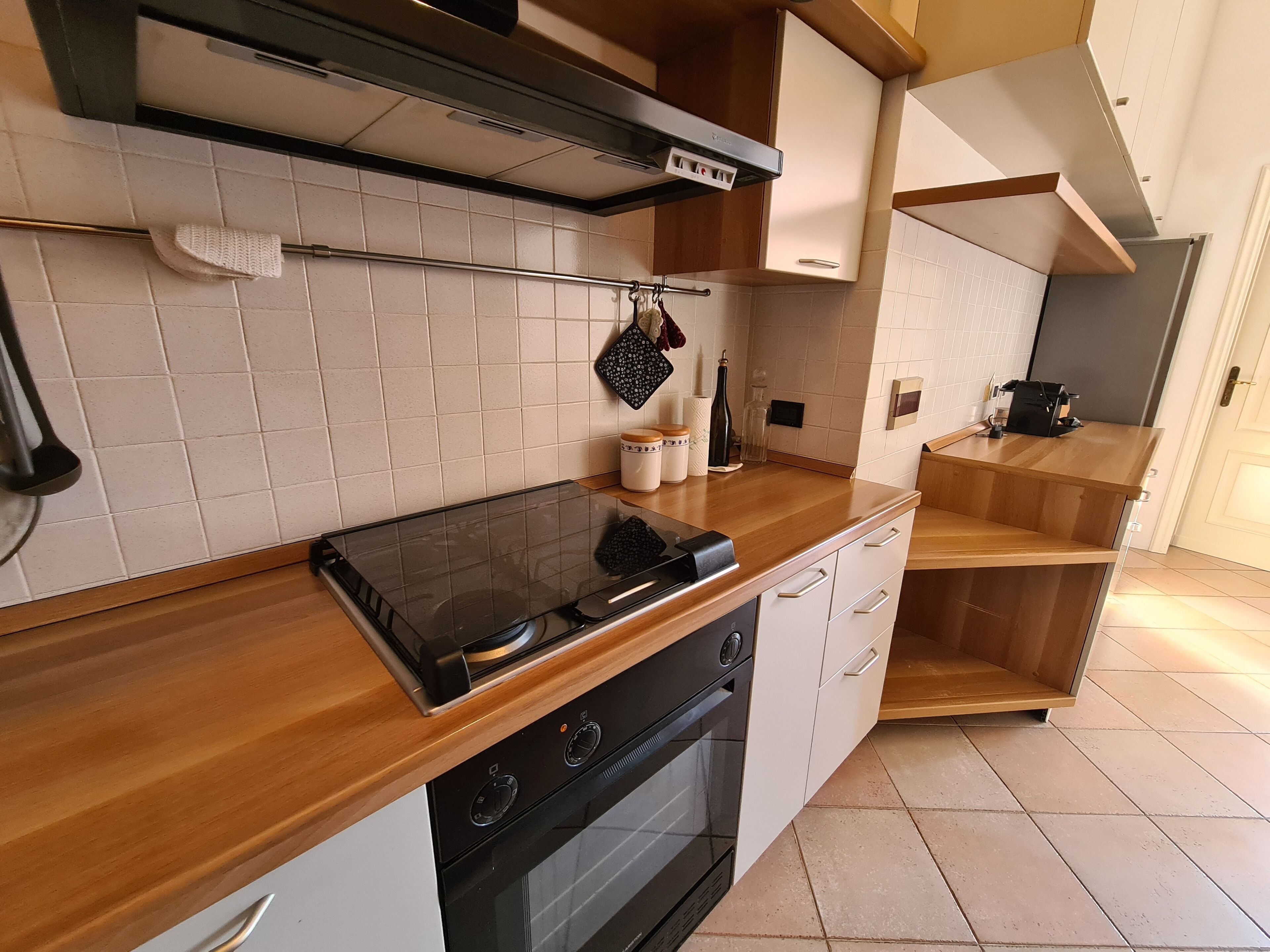 Une cuisine moderne avec un fourneau noir, des armoires blanches et un plan de travail en bois.