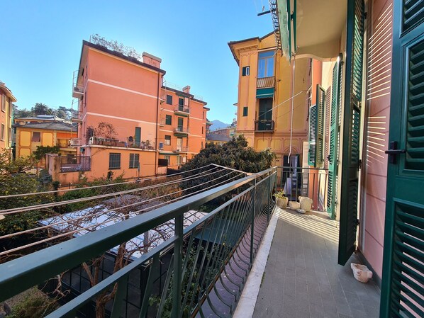 A balcony with a metal railing overlooking a residential area with colorful buildings.