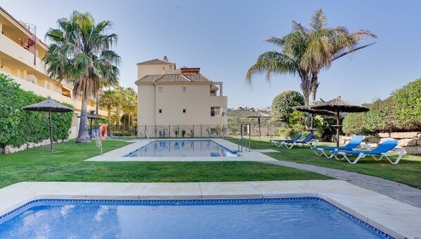 A swimming pool with lounge chairs, palm trees, and a building with a tiled roof. - Unique accommodation with a private pool, sea view, terrace, 300m to Aldea Beach (Manilva)