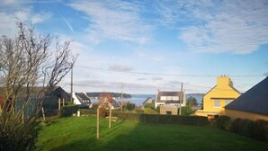 A residential area with houses, a grassy yard, and a body of water in the background. - Maison vue sur mer Avec Jardin (Carantec)
