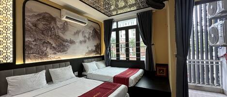 A hotel room with two beds, a large decorative wall, an air conditioning unit, and a view through the window.